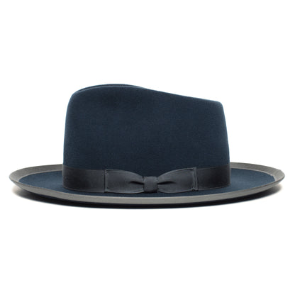 The Goorin Bros. “River Gray” is an American-made wide brim fedora in navy blue, finished with a black ribbon band and small bow, pictured against a plain white background.