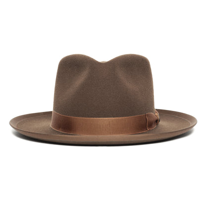 The River Gray fedora by Goorin Bros., American made from premium merino wool, features a wide brim with a stylish brown ribbon band and bow detail, photographed against a white background.