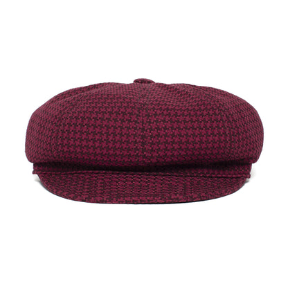 A maroon and black houndstooth-patterned newsboy cap, the “Cold Snap” by Goorin Bros., is shown from the front against a white background. This American-made cabbie flatcap features a German wicking sweatband for added comfort.